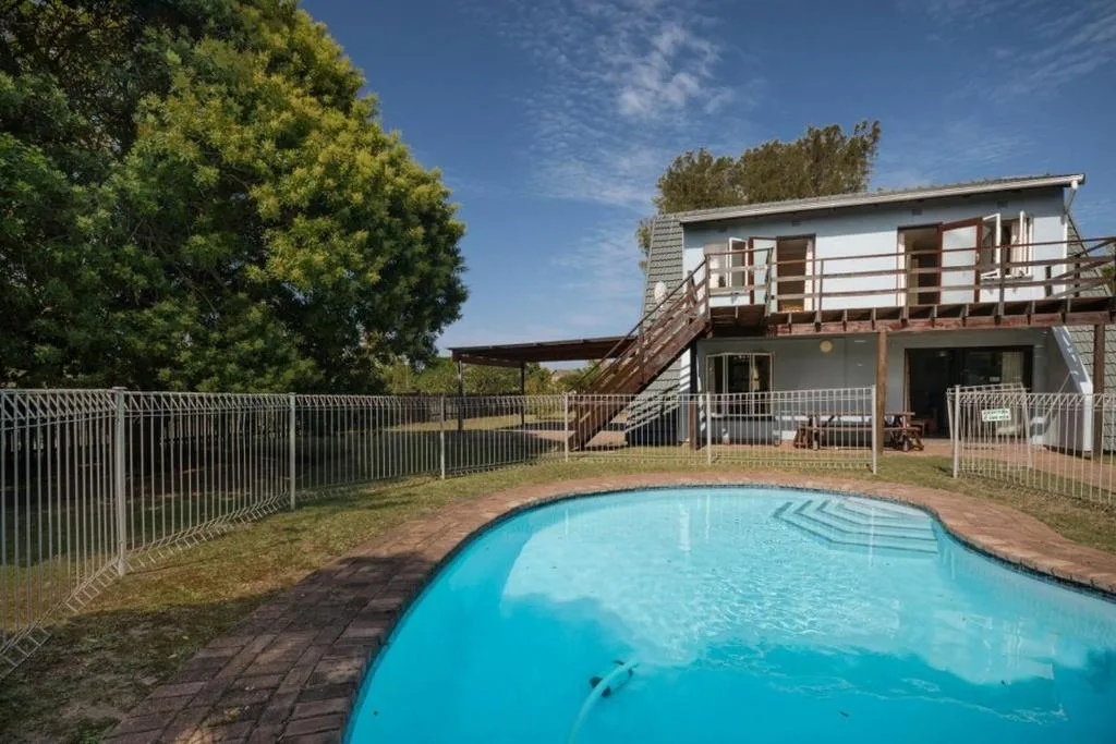 Bright turquoise swimming pool with safety fencing and house behind