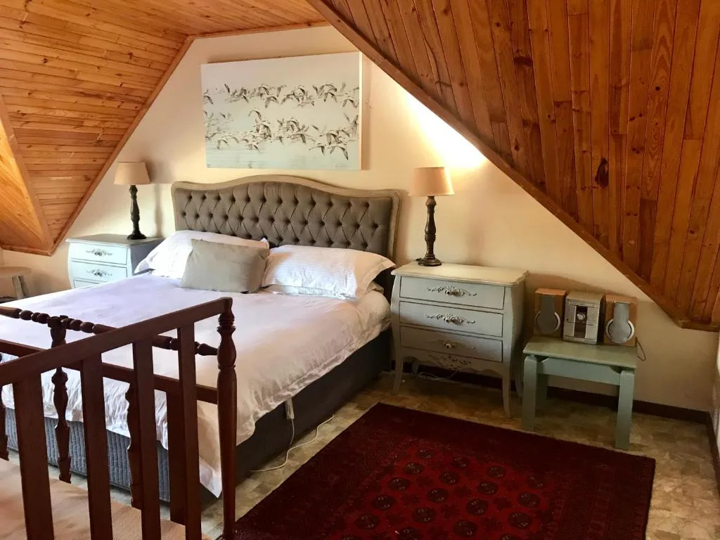 Cozy attic bedroom with wooden beams, upholstered headboard, and matching bedside tables