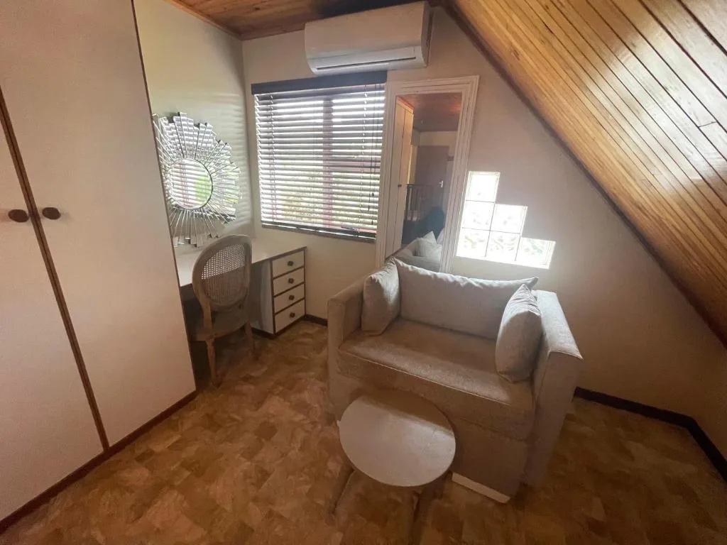 Bright attic bedroom with sloped wooden ceiling and comfortable armchair seating