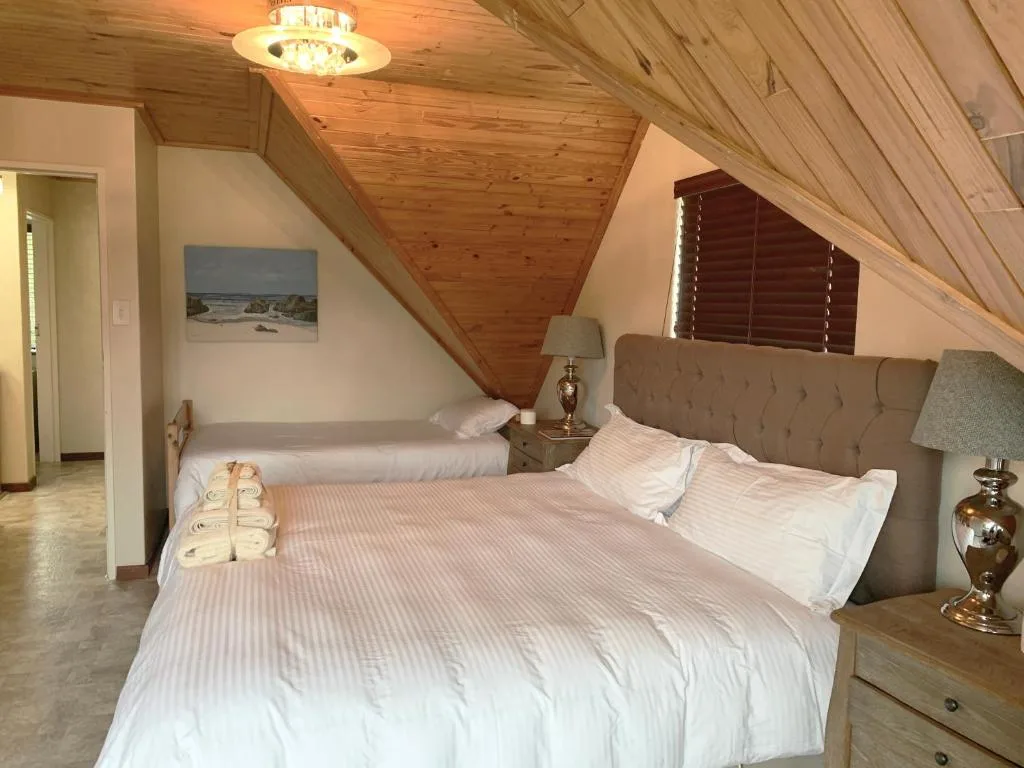 Spacious bedroom with two beds, wooden ceiling, and warm lighting