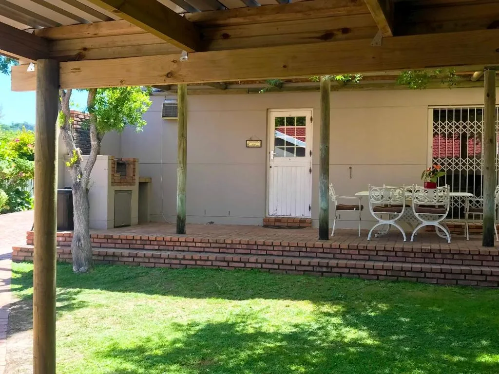 Covered wooden pergola patio with white seating overlooking manicured garden lawn