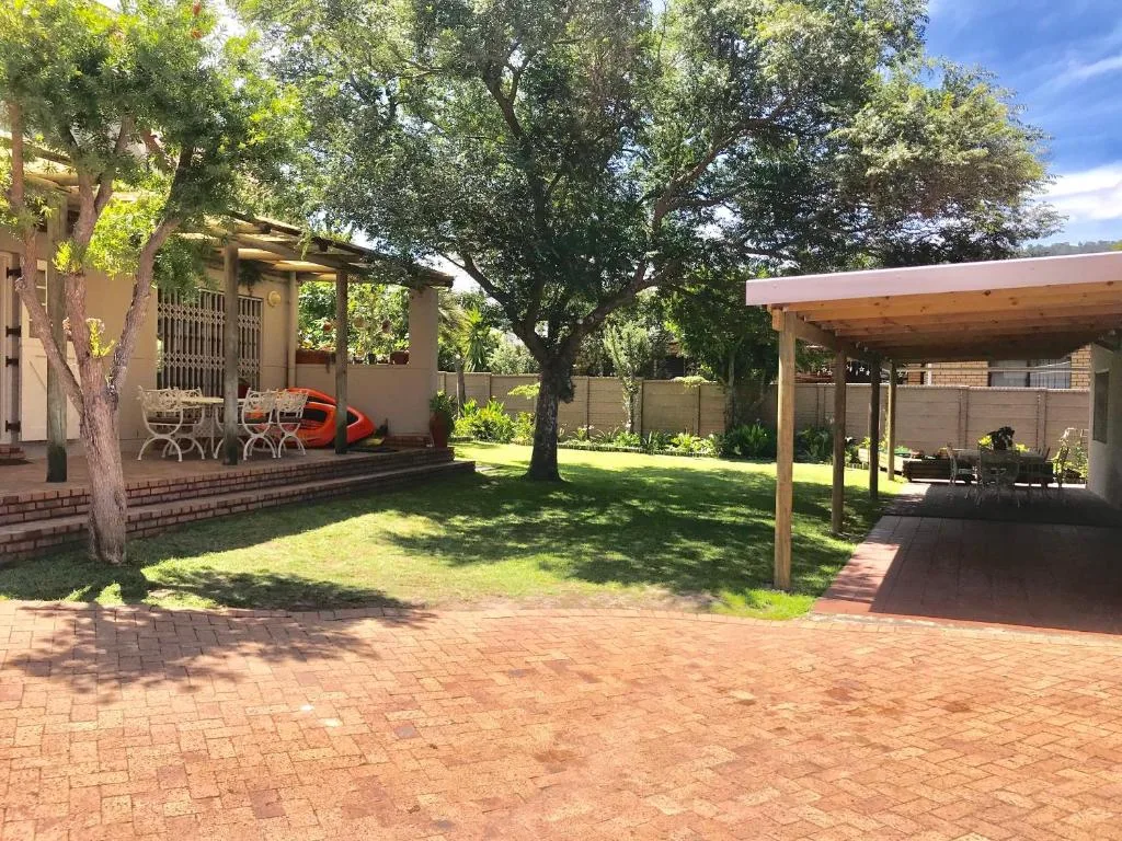Spacious garden with pergolas, mature trees, and brick patio area