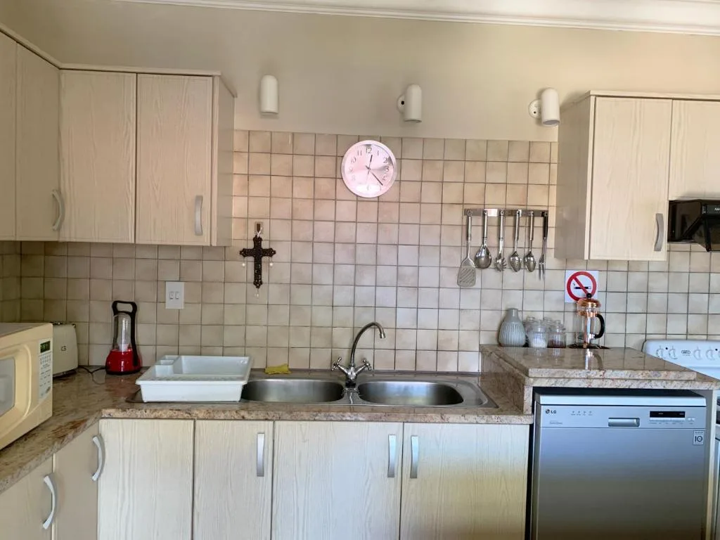 Compact kitchen with cream cabinetry, beige tile backsplash, and stainless steel appliances