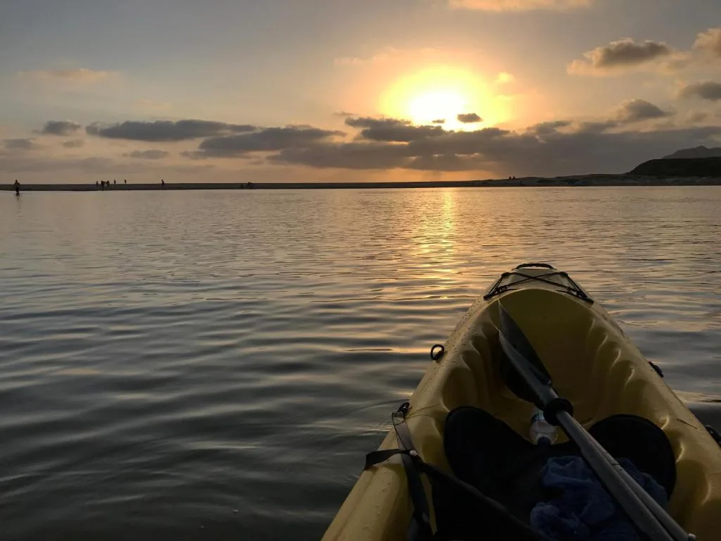 Sunset kayak view across calm lagoon with distant shoreline