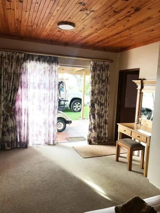 Bright bedroom with wooden ceiling and glass doors opening to driveway