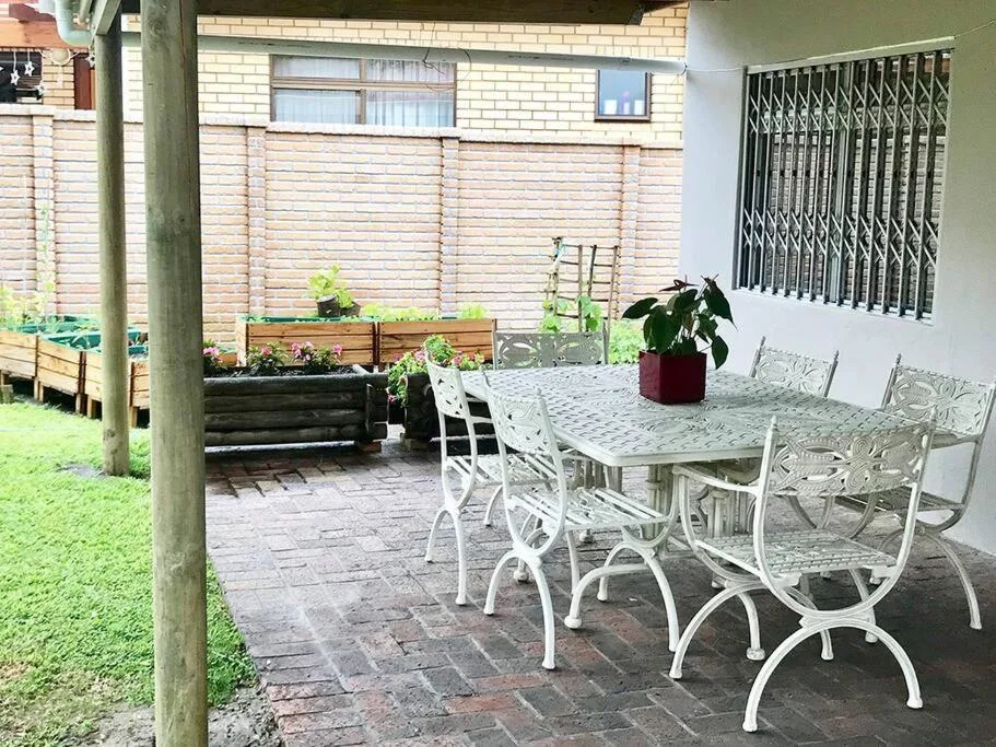 Covered patio with white outdoor dining table and chairs overlooking garden