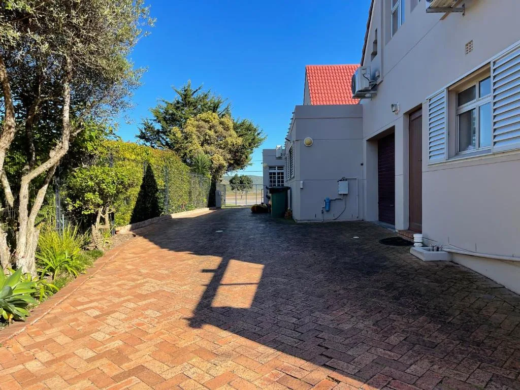 Paved driveway with white buildings and lush garden landscaping