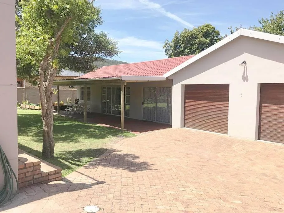 Modern house with red-tiled roof, covered porch, and brick driveway surrounded by trees