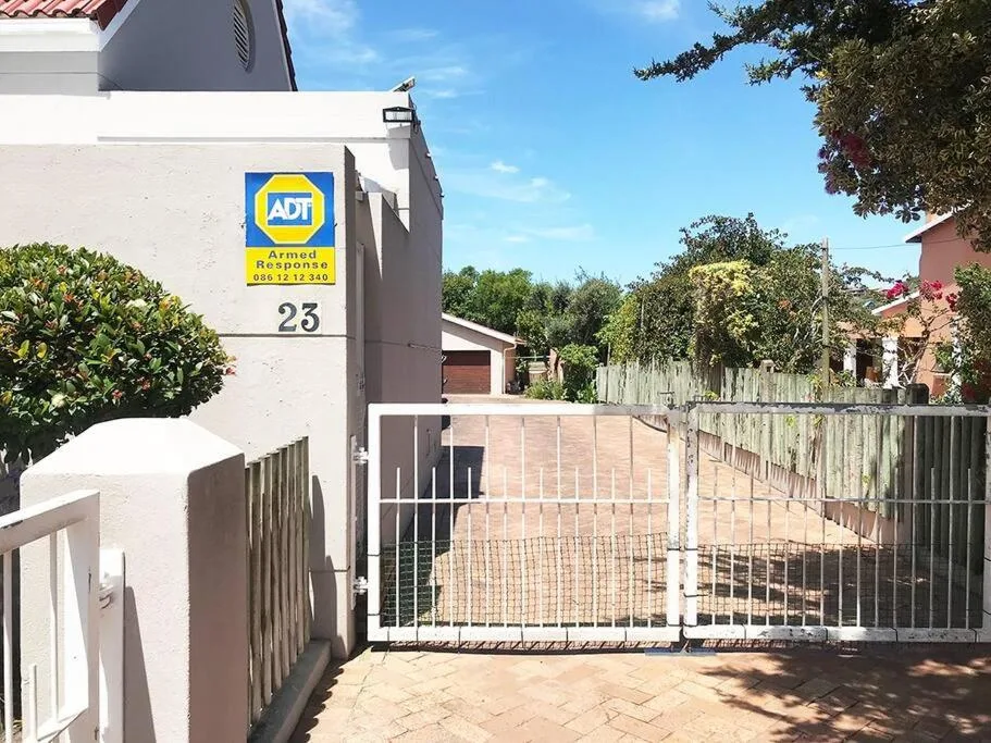Modern white house entrance with metal gates and numbered address sign