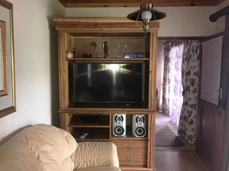 Living room with flat-screen TV in wooden entertainment unit and cream sofa