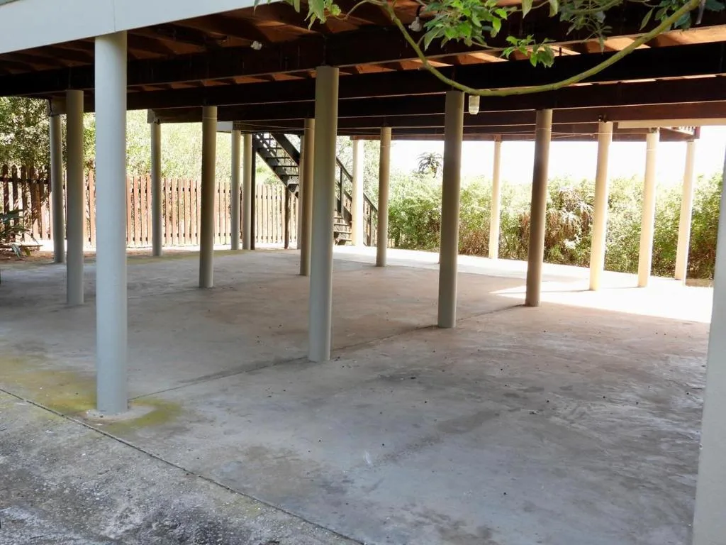 Spacious covered outdoor patio with concrete floor and wooden beams
