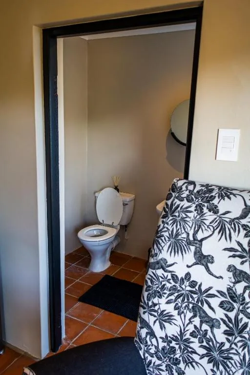 Compact ensuite bathroom with toilet and terracotta floor tiles