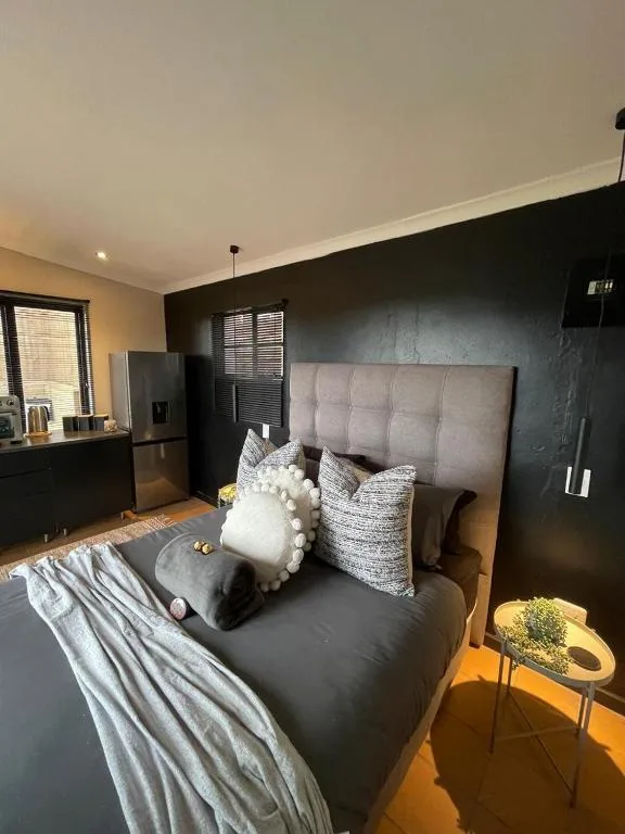 Modern bedroom with gray upholstered headboard and black feature wall