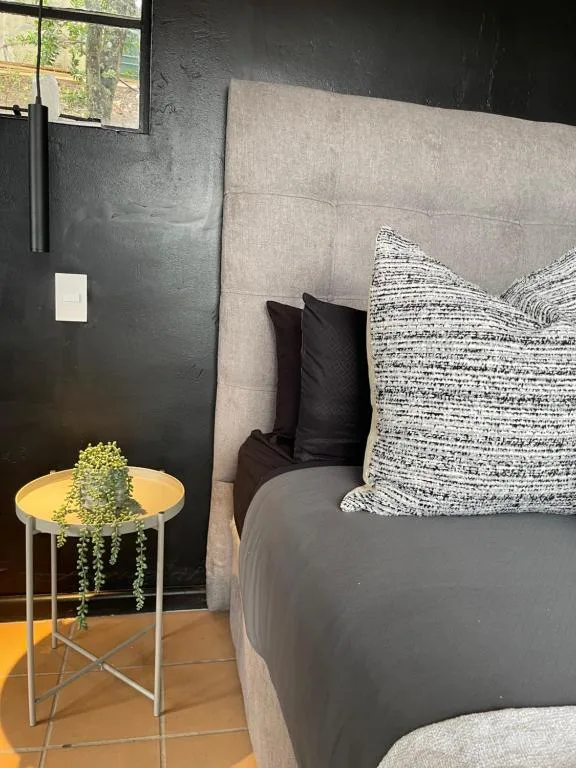 Modern bedroom with upholstered headboard, textured pillows, and potted plant accent