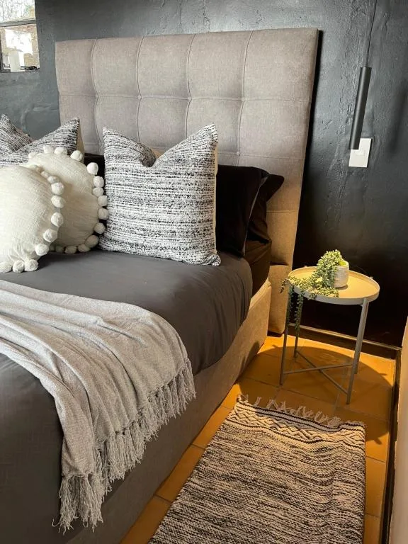 Modern bedroom with upholstered headboard, styled pillows, and bedside table