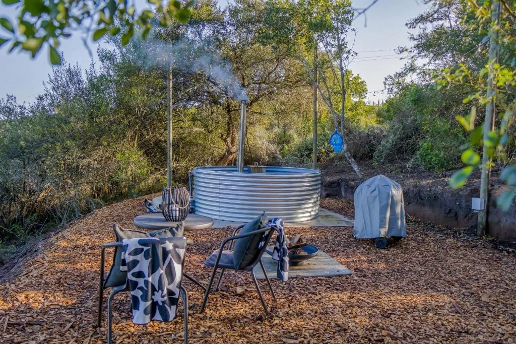 Outdoor seating area with chairs and metal water tank surrounded by trees