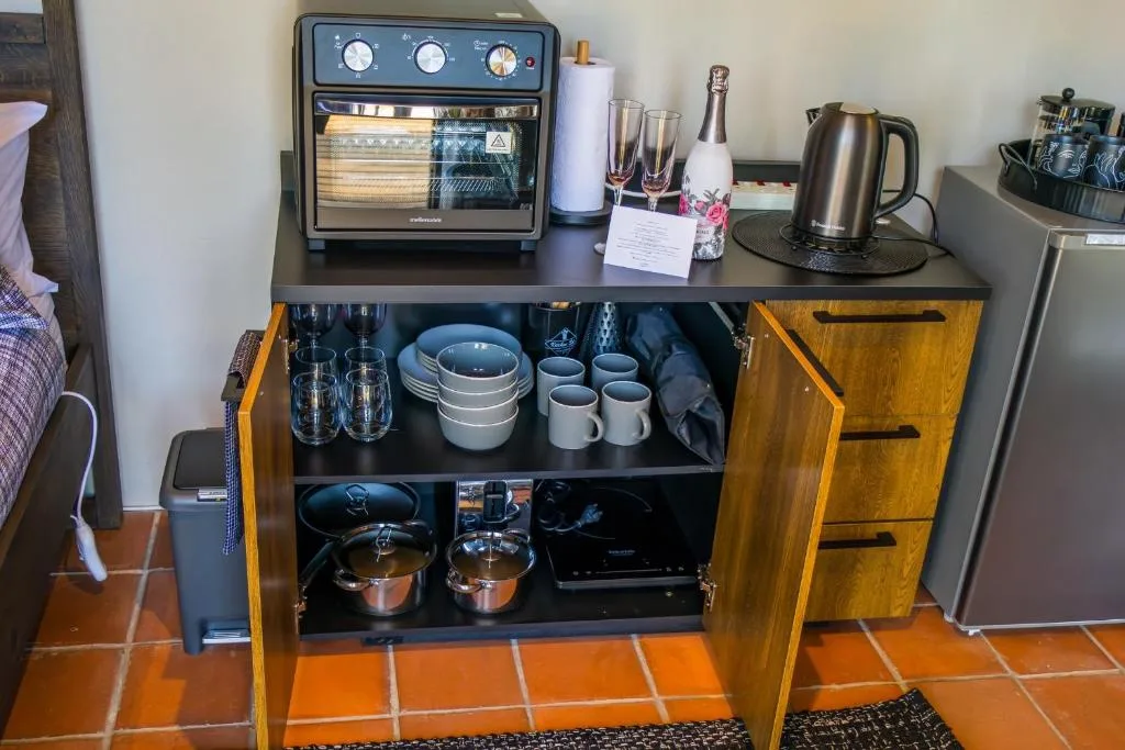 Kitchen counter with toaster oven, kettle, and open cabinetry displaying dinnerware