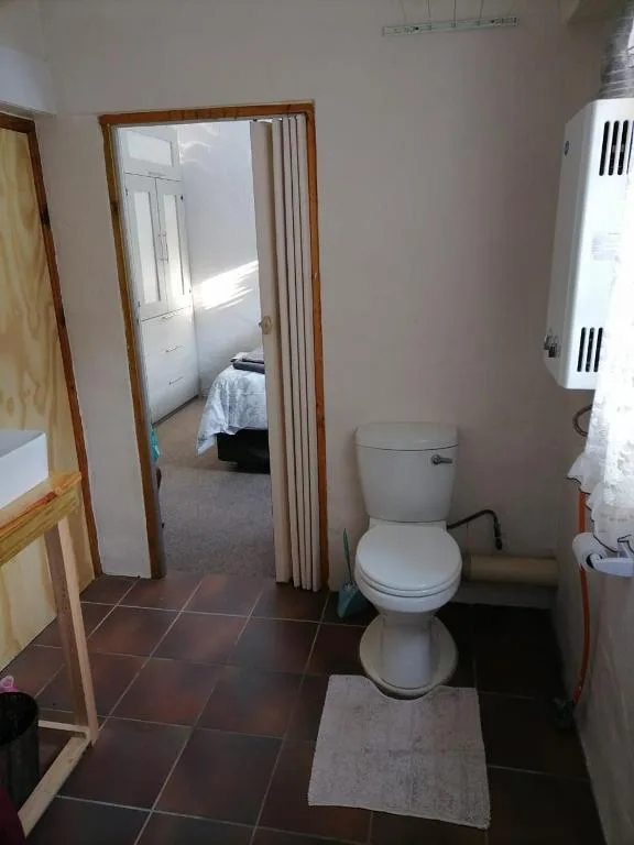 Simple bathroom with white toilet, tiled floor, and open doorway