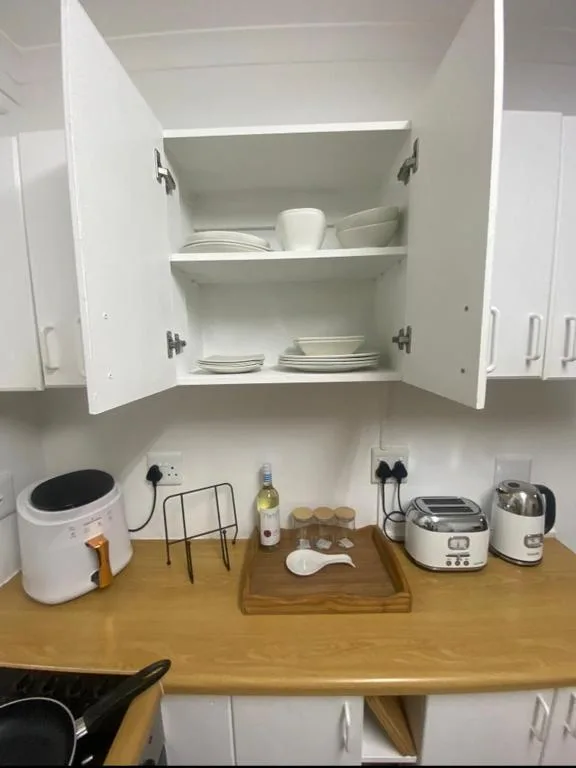 Open kitchen cabinet displaying white dishes and tableware above wooden counter