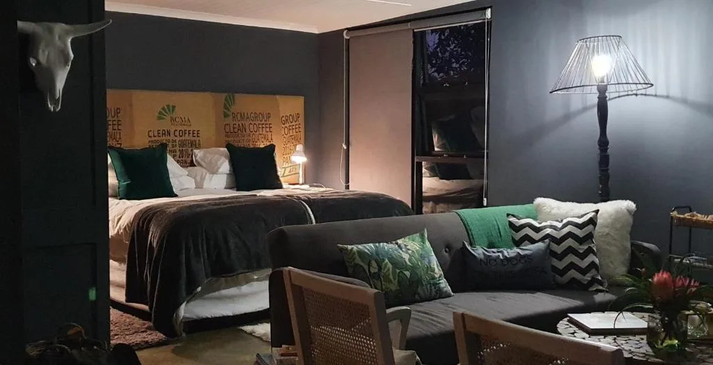 Modern bedroom with dark walls, queen bed, and integrated lounge seating area