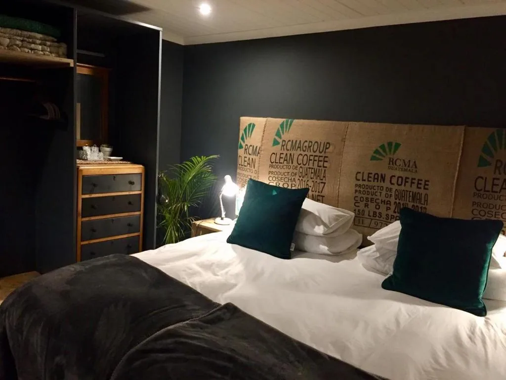 Modern bedroom with white bedding, green pillows, and coffee sack headboard