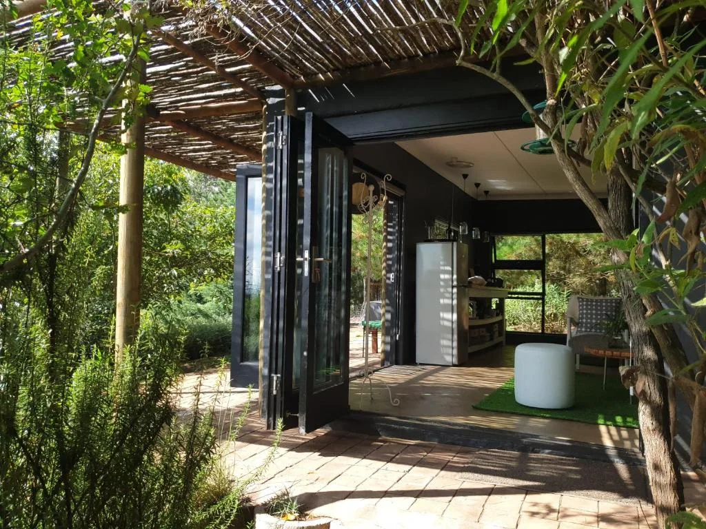 Shaded patio with pergola, modern black bi-fold doors, lush greenery
