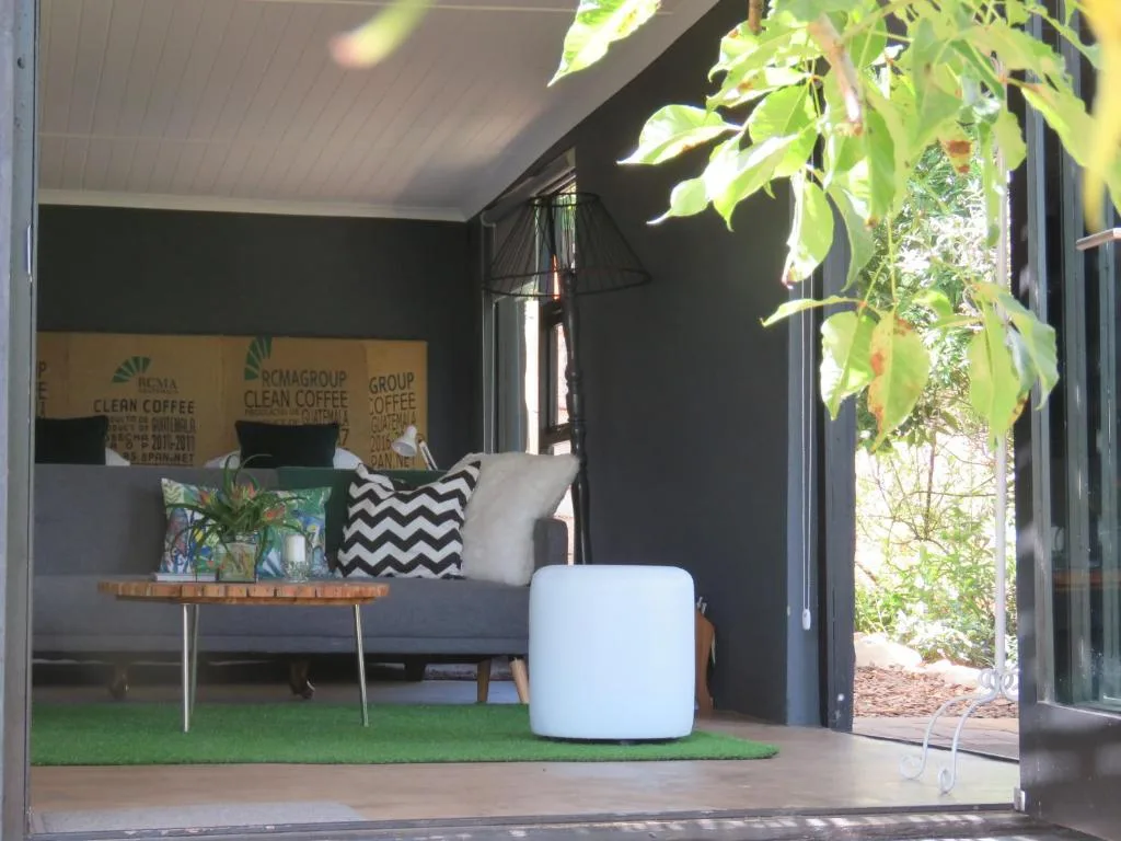 Covered outdoor seating area with sofa, poufs, and hanging plants