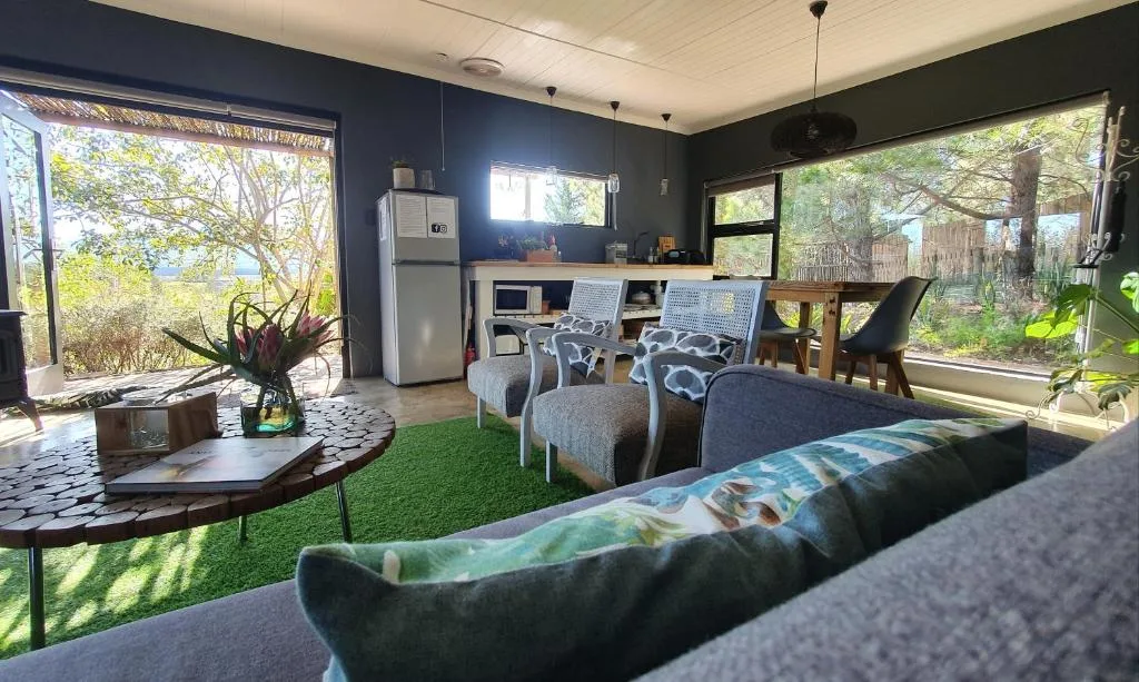 Open-plan lounge with sofas, kitchenette, and garden views through large windows