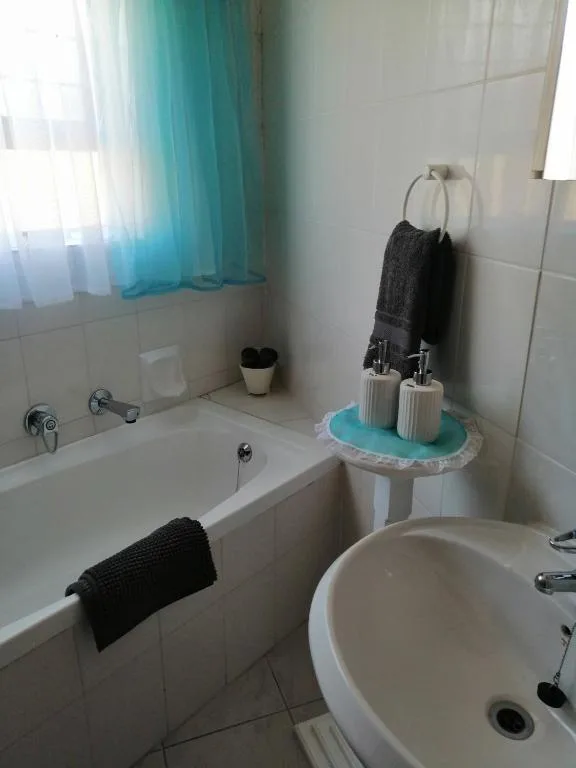 Clean bathroom with bathtub, sink, and turquoise accents throughout