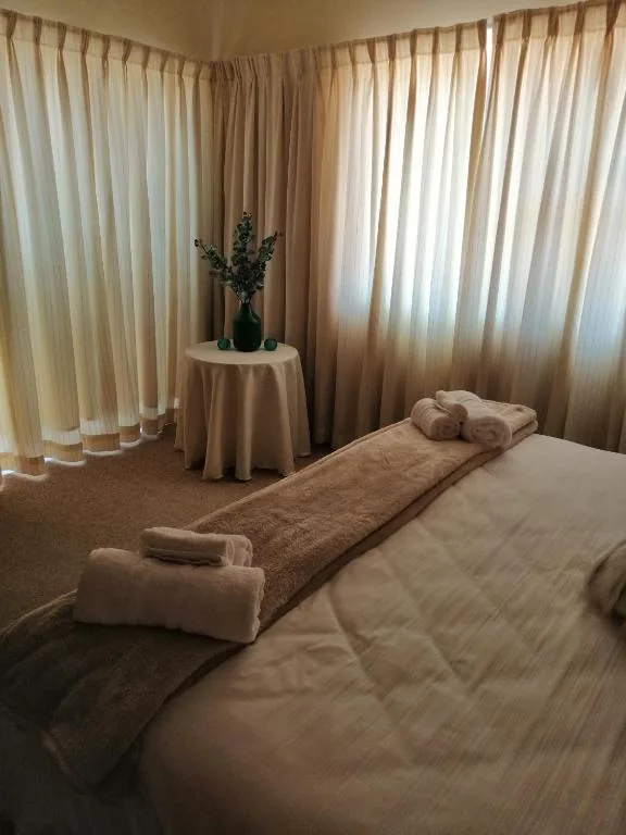 Bright bedroom with queen bed, rolled towels, and cream curtains