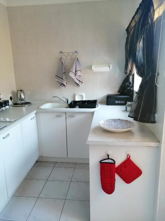 Compact kitchen with white cabinetry, sink, and tiled flooring