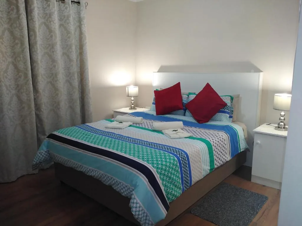 Bright bedroom with colorful striped bedding and red accent pillows