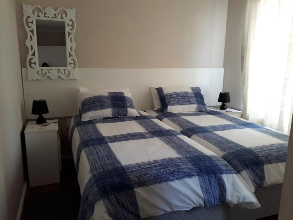 Twin beds with blue and white checkered bedding and decorative mirror