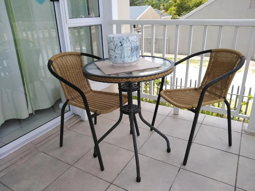 Outdoor balcony with wicker chairs and small round table overlooking trees