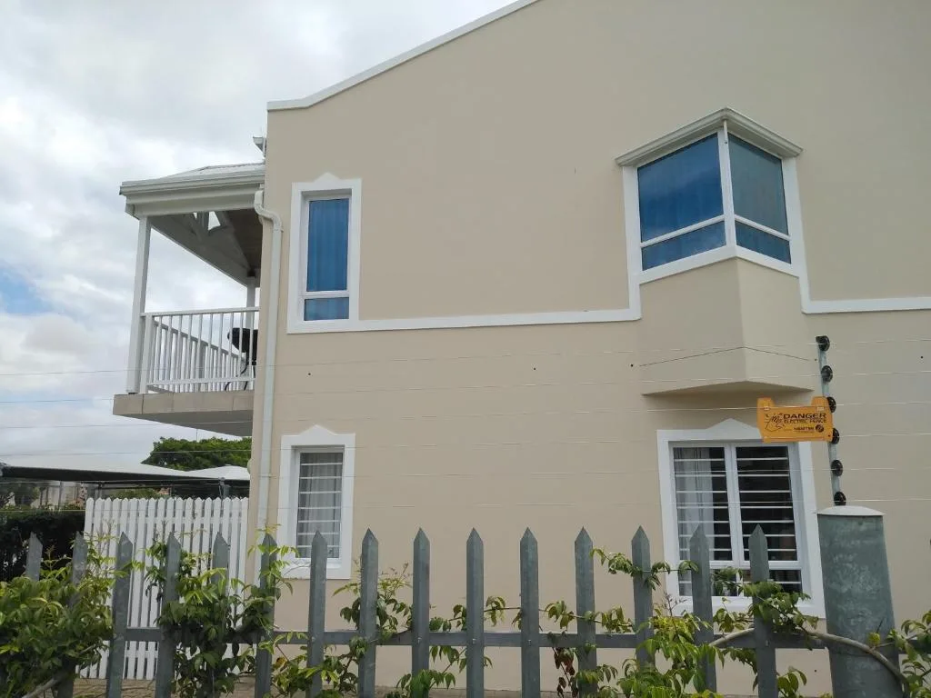 Modern two-story beige house with white trim and upper deck on Garden Route