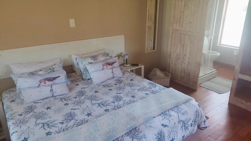 Bedroom with double bed, bird-patterned bedding, white headboard, and natural light