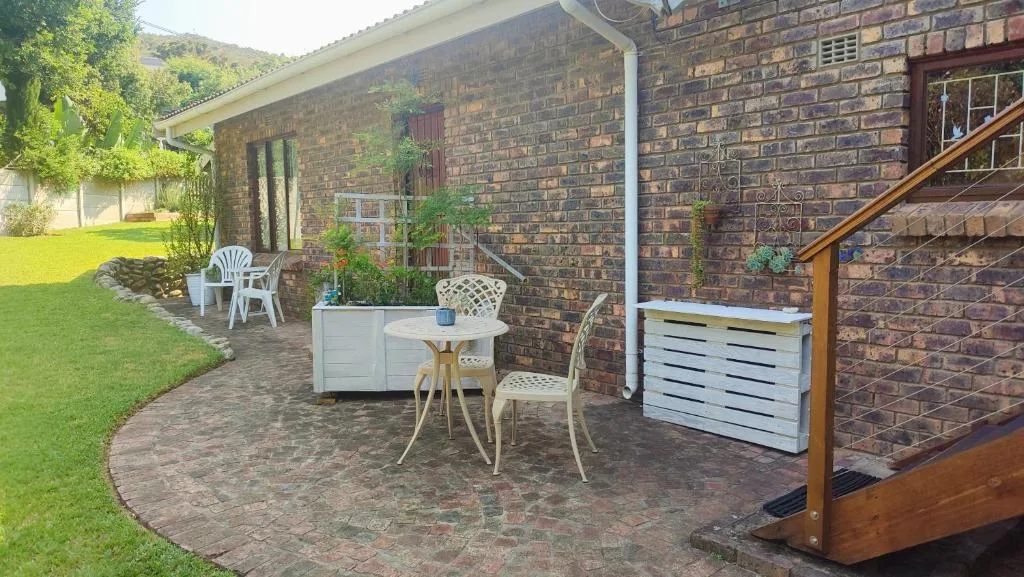 Brick patio with seating area, potted plants, and manicured garden lawn