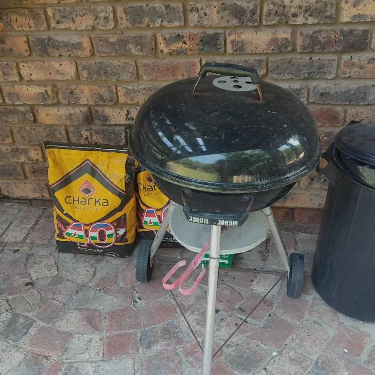 Charcoal braai grill with briquettes beside brick wall