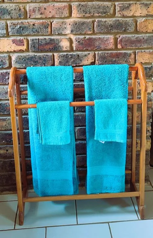 Bright turquoise towels displayed on wooden rack against brick wall