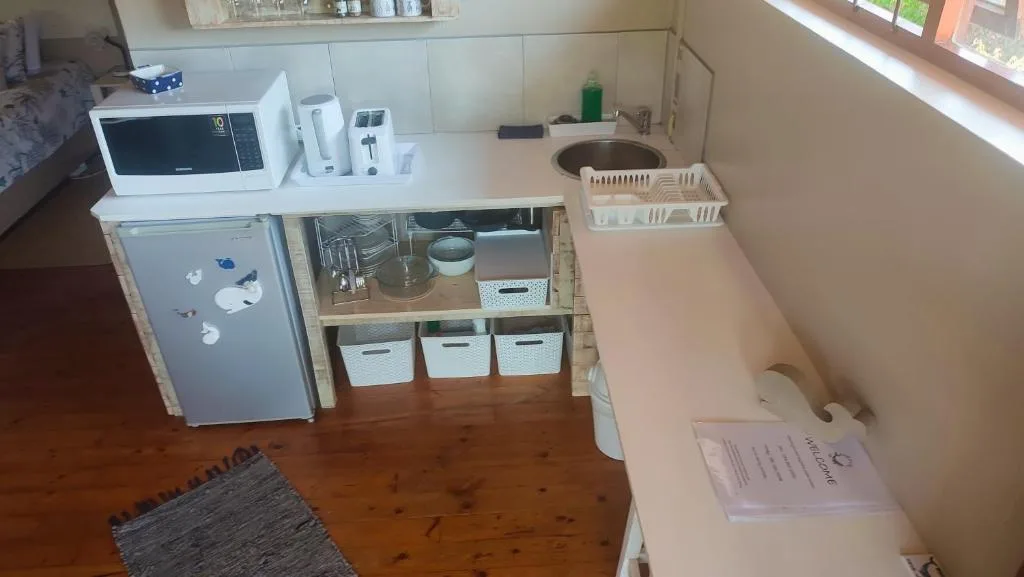 Compact kitchen with microwave, refrigerator, sink, and organized storage baskets