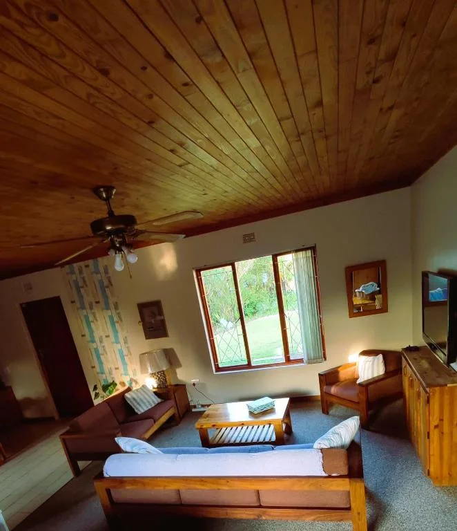 Spacious lounge with wooden ceiling, comfortable seating, and garden views