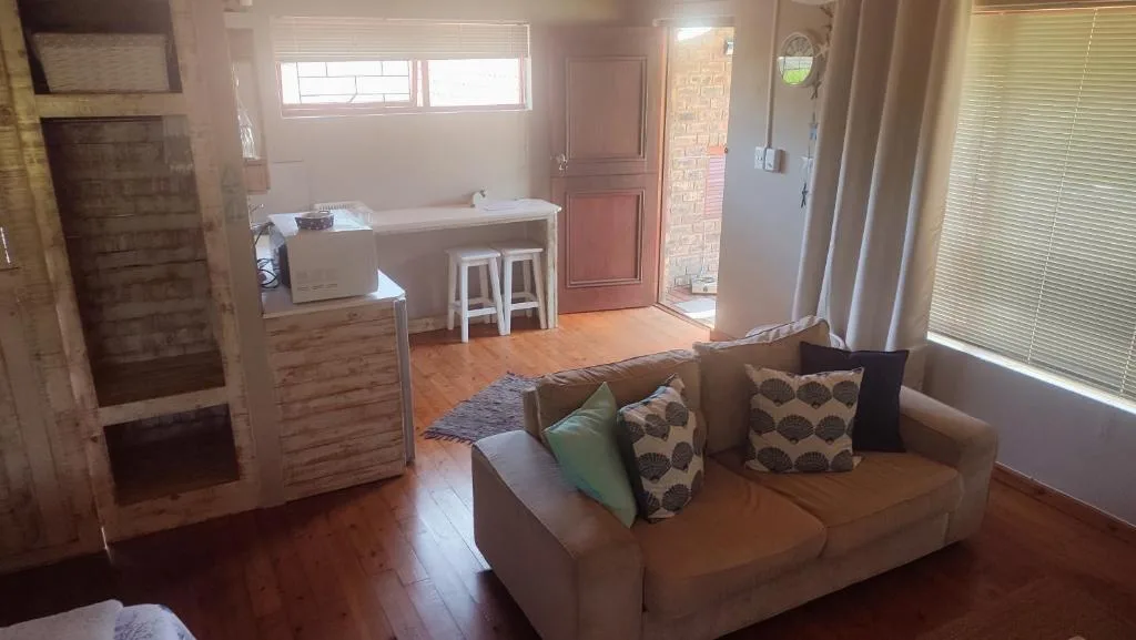 Open-plan lounge with beige sofa, patterned cushions, wooden floors