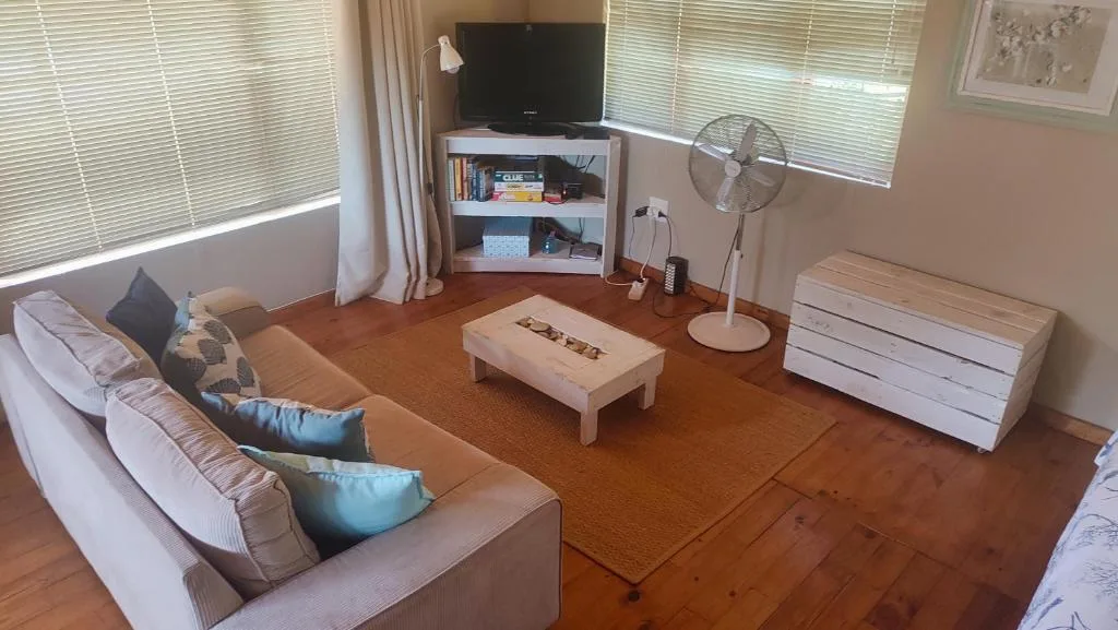 Spacious living room with cream sofa, TV, and wooden floors