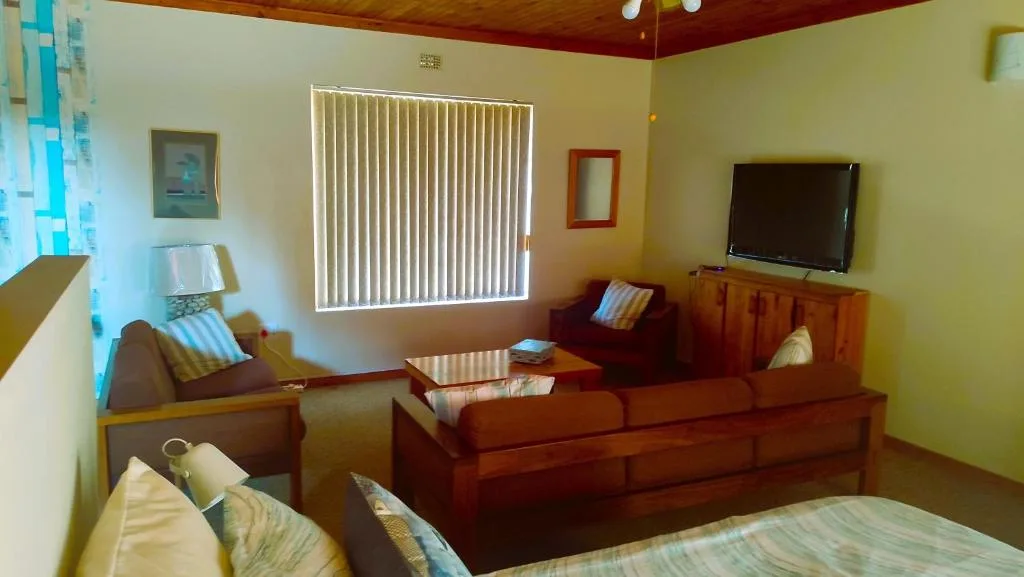 Spacious lounge with wooden furniture, TV, and natural light from large windows