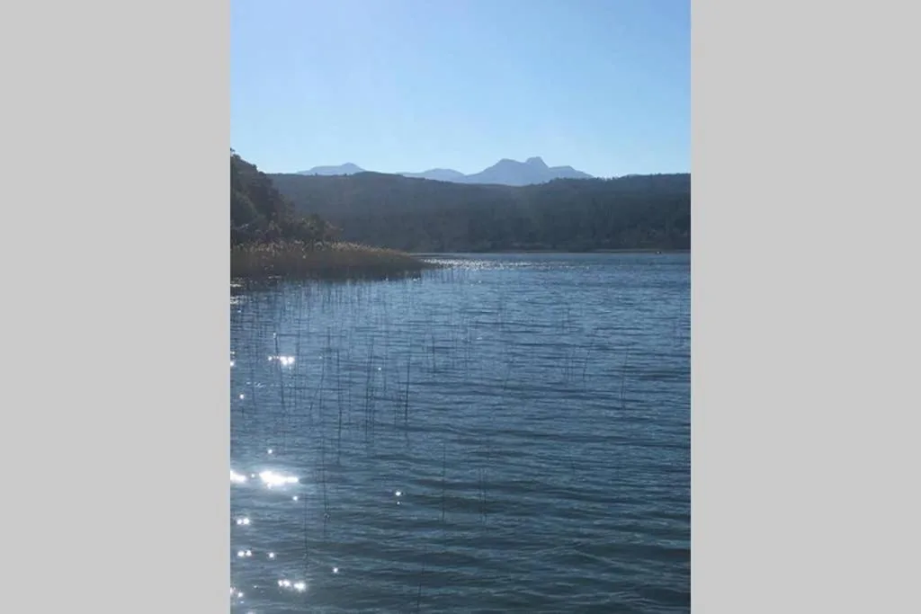 Scenic lagoon view with mountains and forested shoreline under clear blue sky