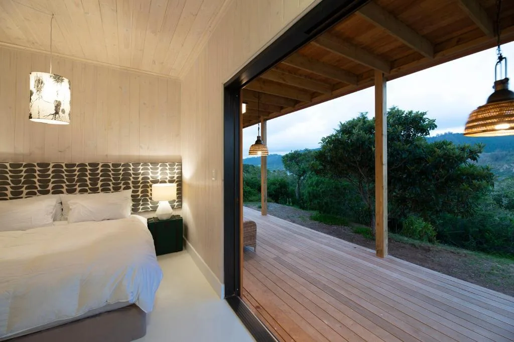 Modern bedroom with queen bed overlooking wooden deck and mountain views