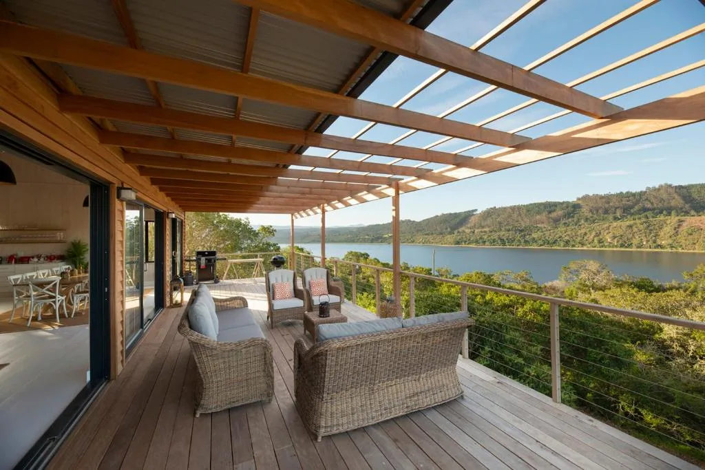 Wooden deck with pergola, wicker seating, and stunning lagoon views
