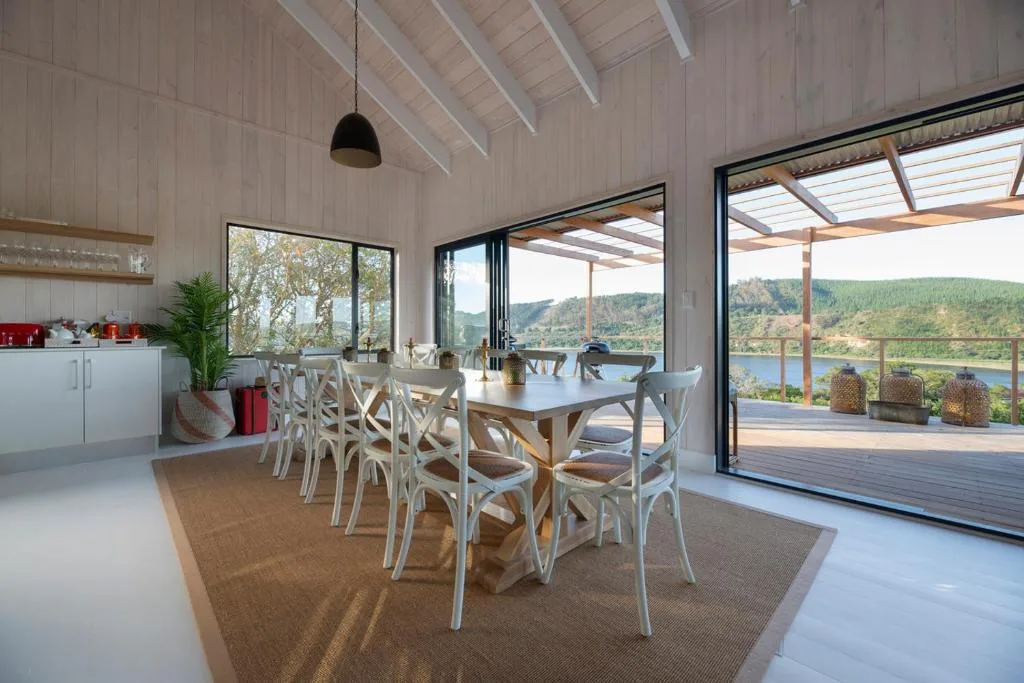 Modern dining room with white chairs, wooden table, and scenic lake views