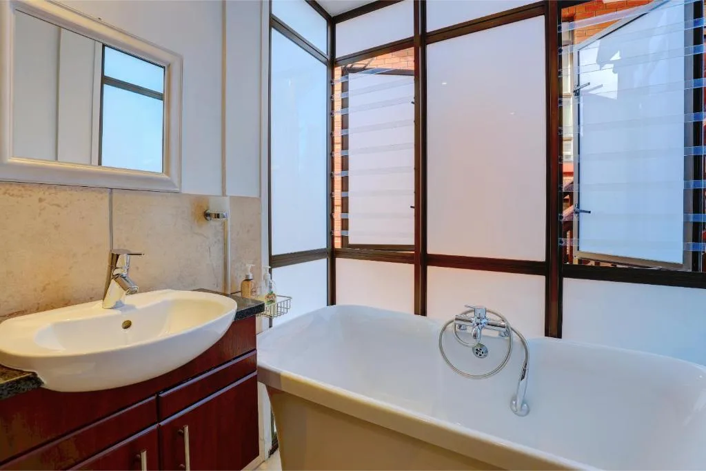 Spacious bathroom with round sink vanity and freestanding bathtub with natural light