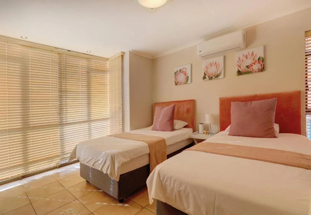 Twin bedroom with coral headboards, pink bedding, and floral wall art
